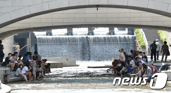 전국이 대부분 지역에 폭염특보가 내려진 22일 오후 서울 청계천에서 시민들이 물속에 발을 담그며 더위를 식히고 있다. / 뉴스1